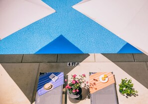Una piscina al aire libre, sombrillas, sillones reclinables de piscina
