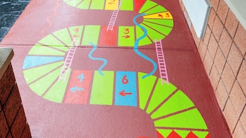 Un camino de juego de mesa colorido sobre pavimento mojado, con un punto de partida marcado por un círculo rojo.
