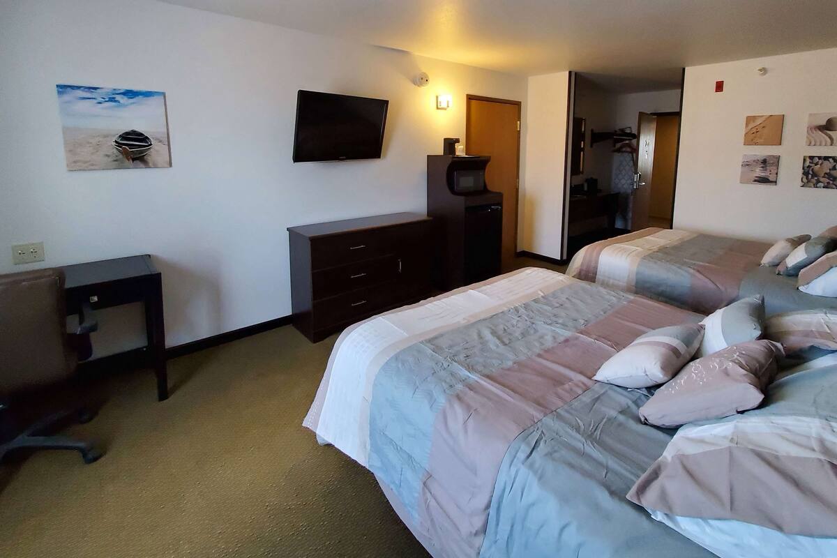 Hotellihuone, jossa on kaksi sänkyä, televisio, työpöytä ja lipasto.