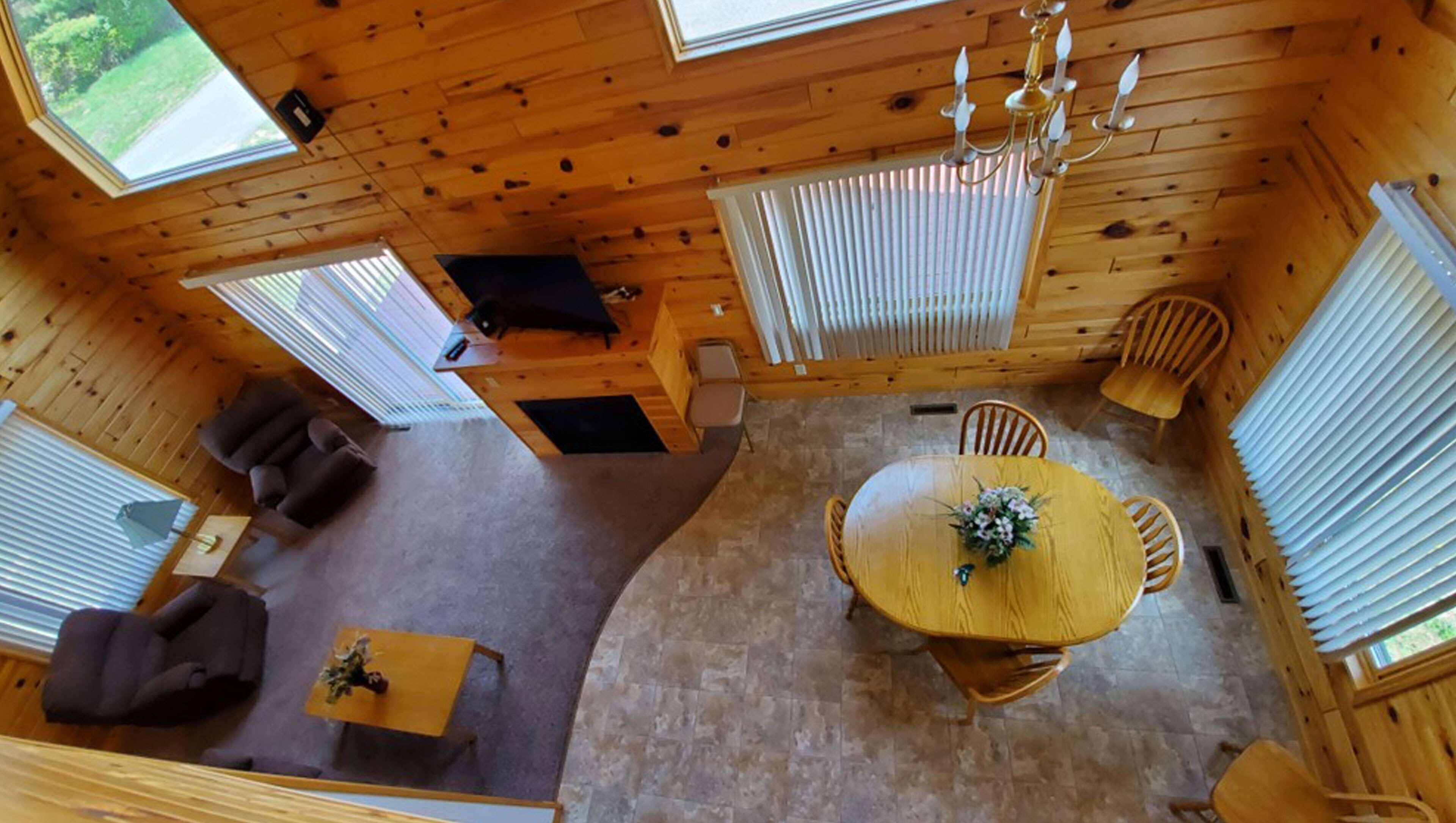 En stuga med ett matområde, en soffa och en kristallkrona.