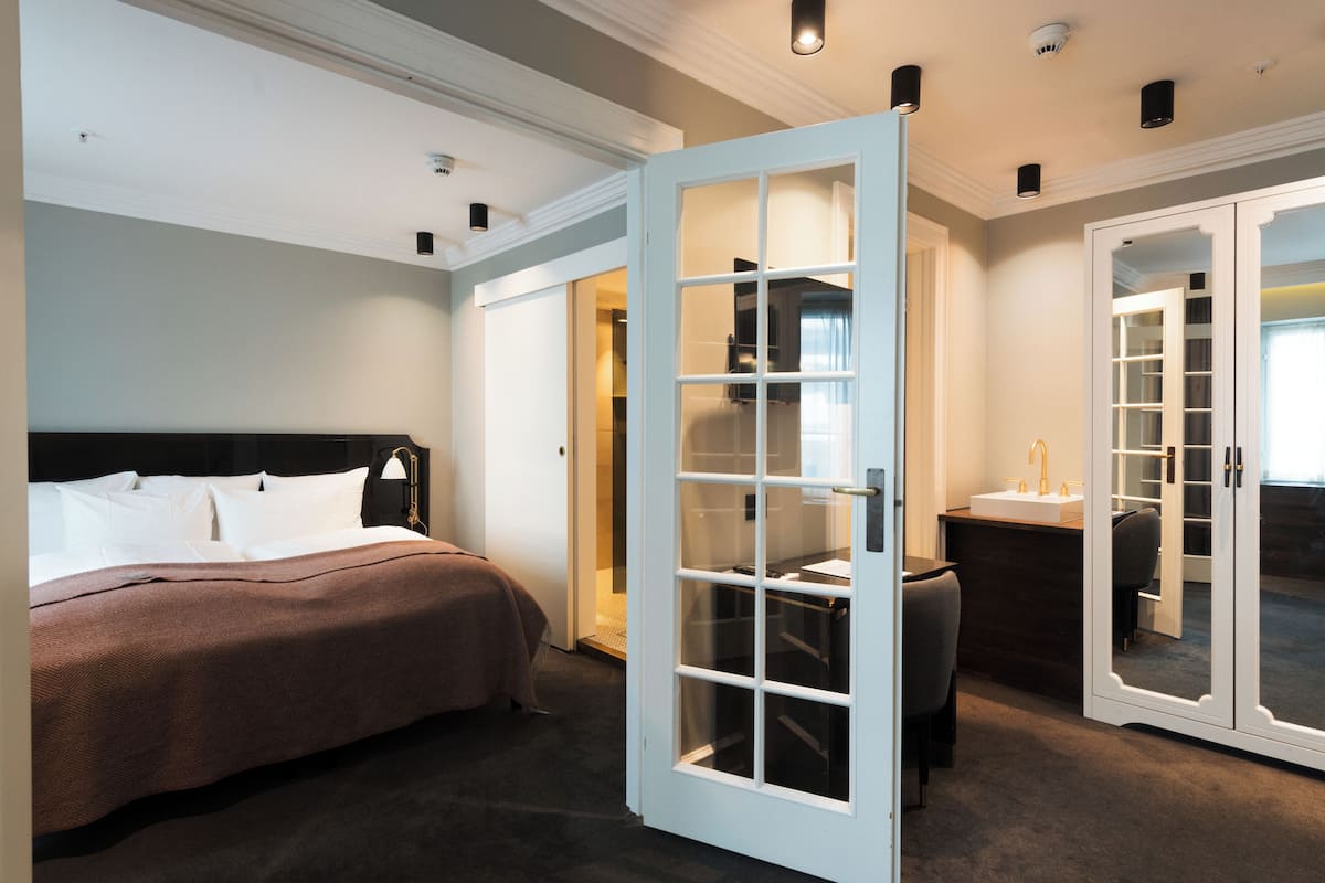 A hotel room with a bed, a desk, a chair, a wardrobe, and a bathroom.