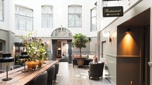 A spacious dining area with a long wooden table, multiple chairs, and a central seating arrangement. - Hotel SKT. Annæ (Copenhagen)