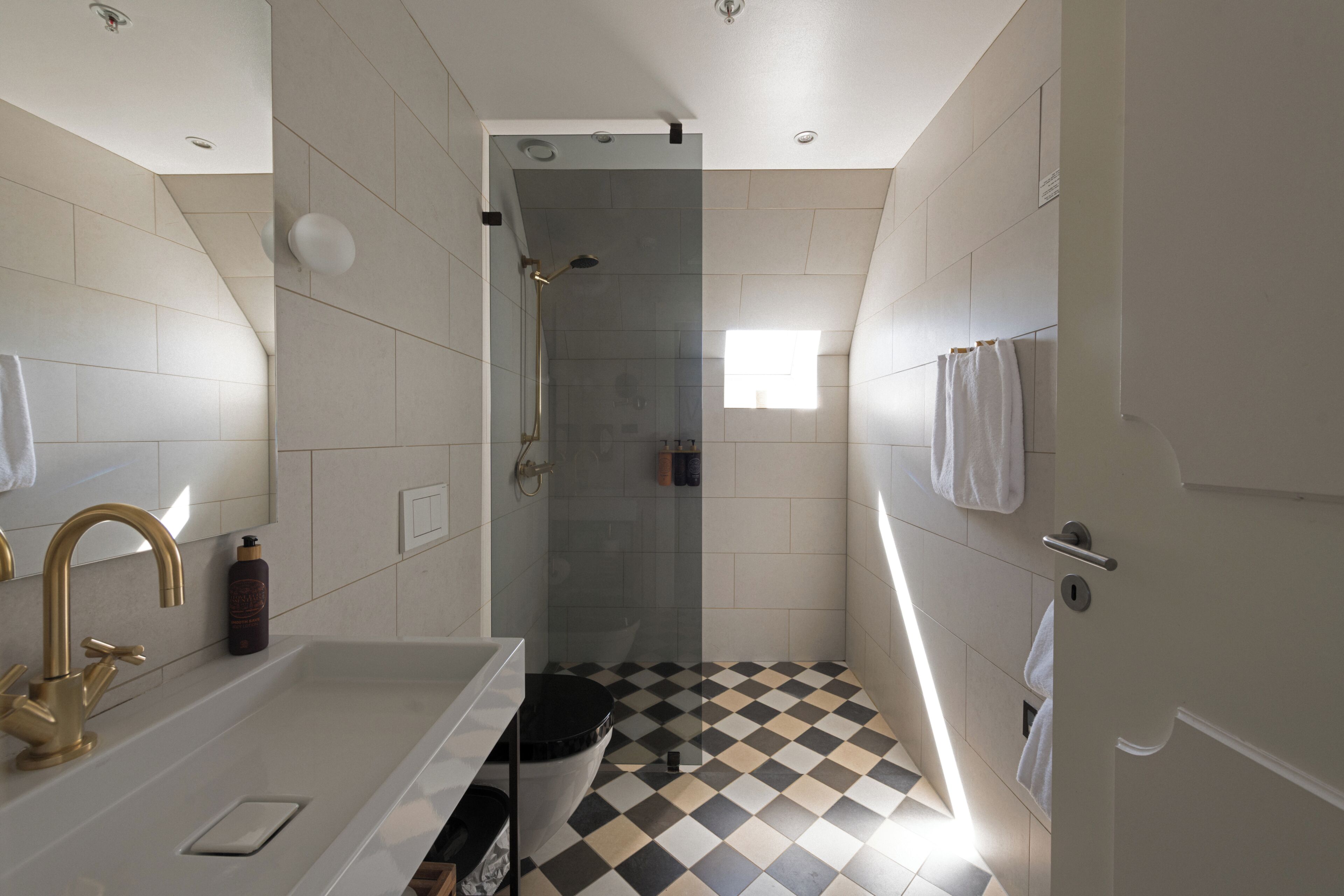 Un baño con lavamanos blanco, ducha y piso a cuadros.