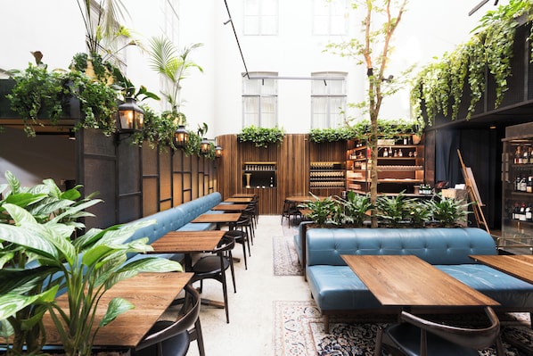 A restaurant with wooden tables, blue cushioned seating, and hanging plants.