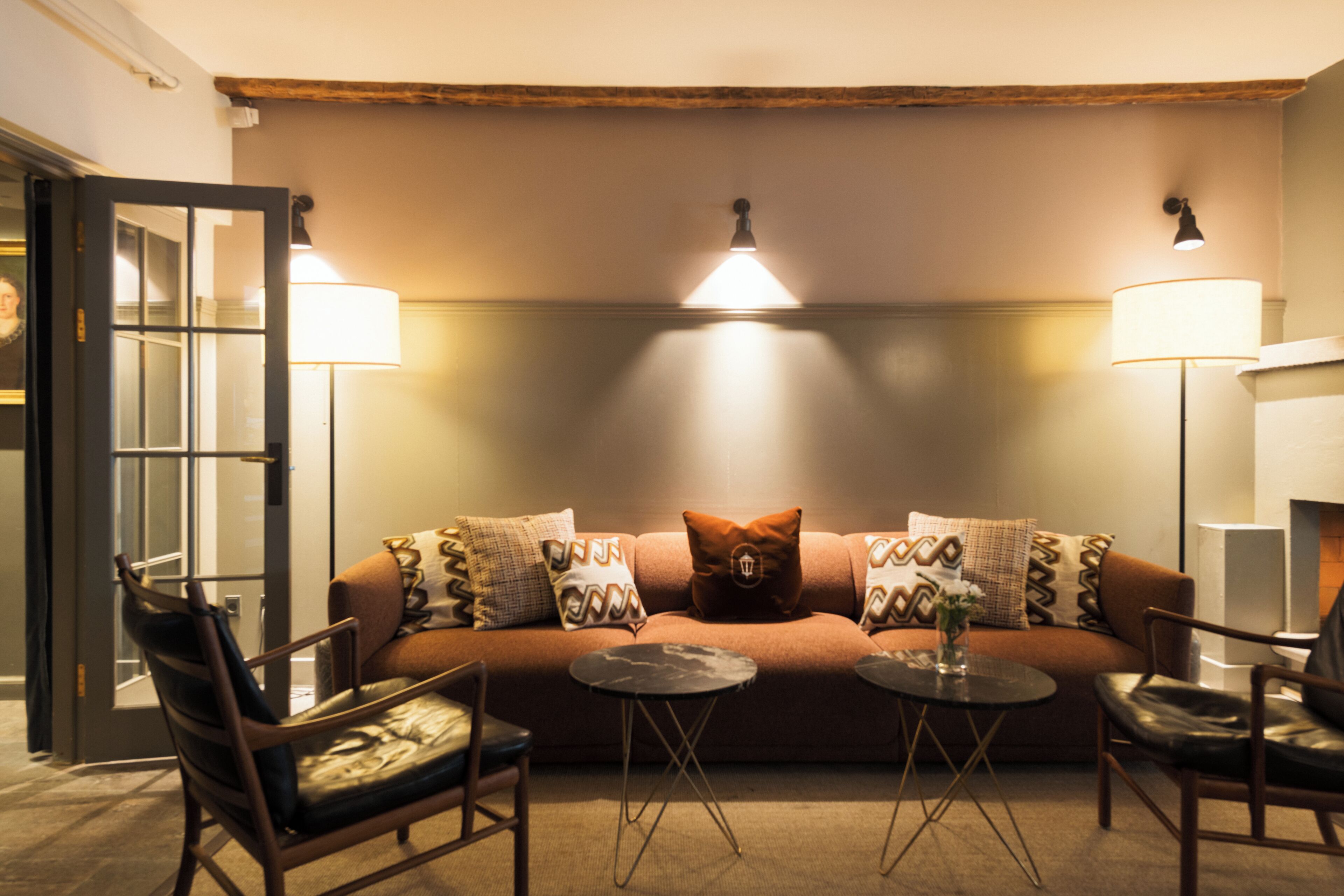 Ein gemütliches Zimmer mit einer Couch, zwei Sesseln, einem kleinen Couchtisch und zwei Stehlampen.