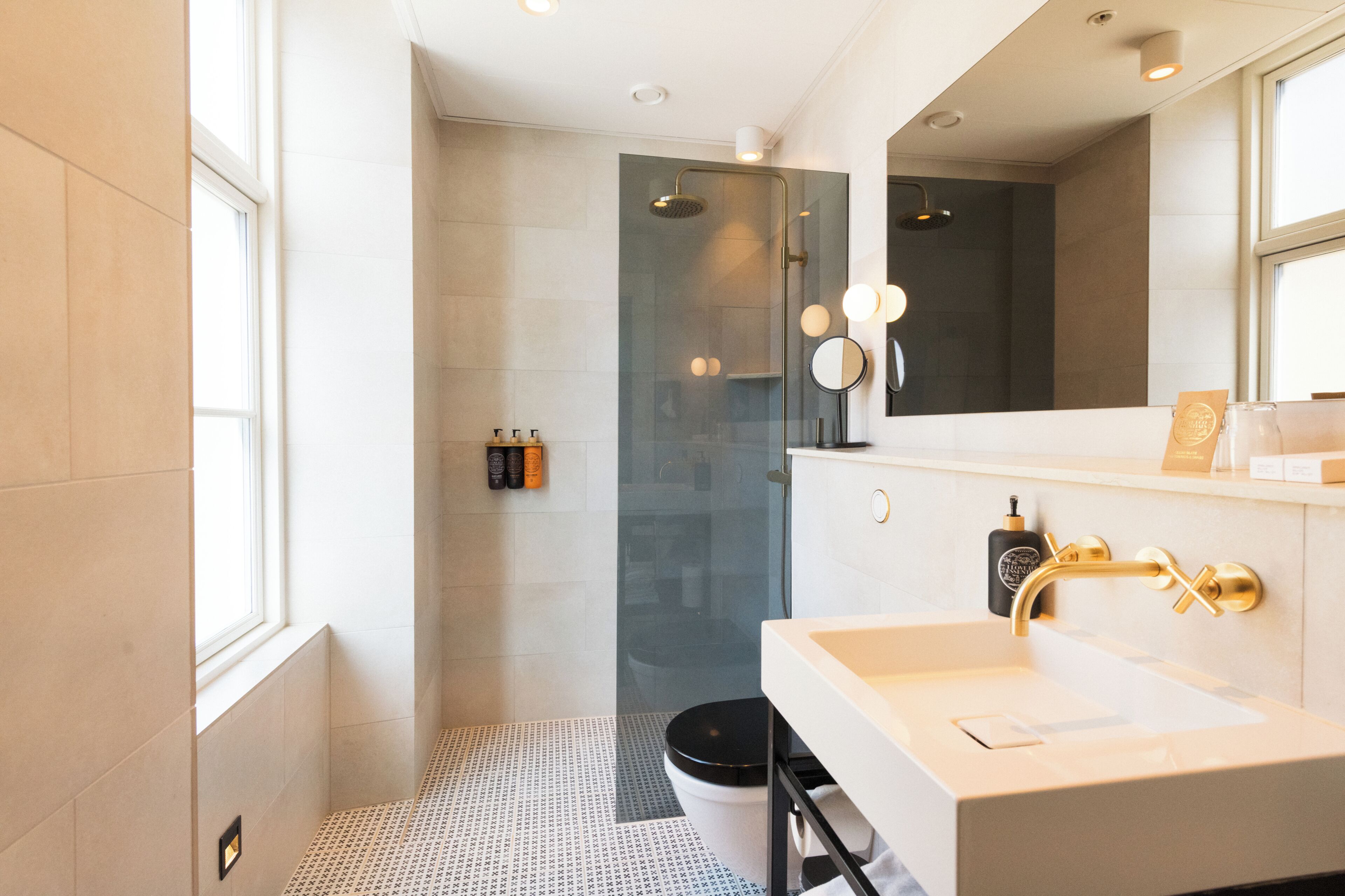 A modern bathroom with a large mirror, a shower, and a sink.
