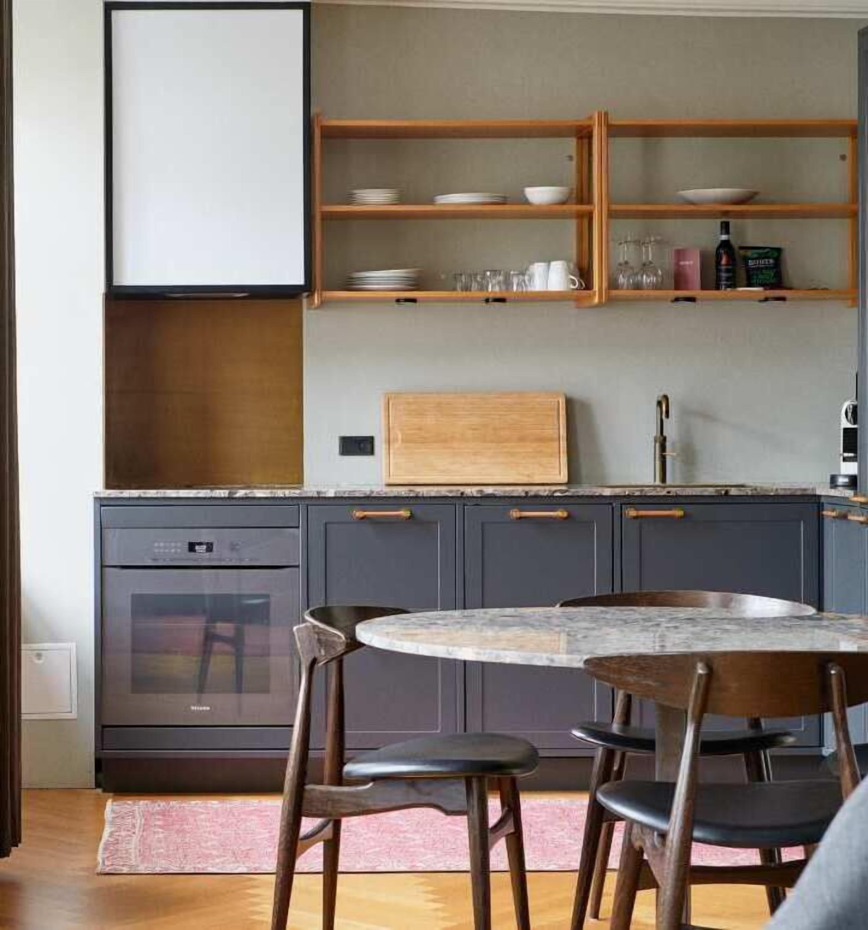 Een keuken met donkere kastjes, een houten aanrecht en een ronde tafel met stoelen.
