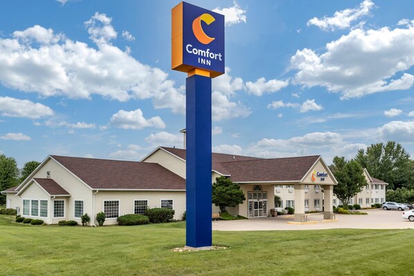Un hotel Comfort Inn con un letrero azul llamativo, un edificio de dos pisos con techo marrón y un césped bien cuidado.