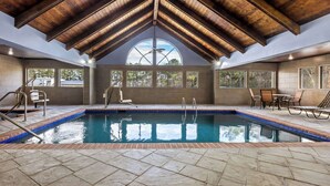 Une piscine intérieure dotée d’un plafond en voûte et de grandes fenêtres.