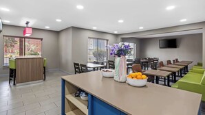 Un espace repas moderne doté d’un long comptoir, de plusieurs tables et de sièges verts.