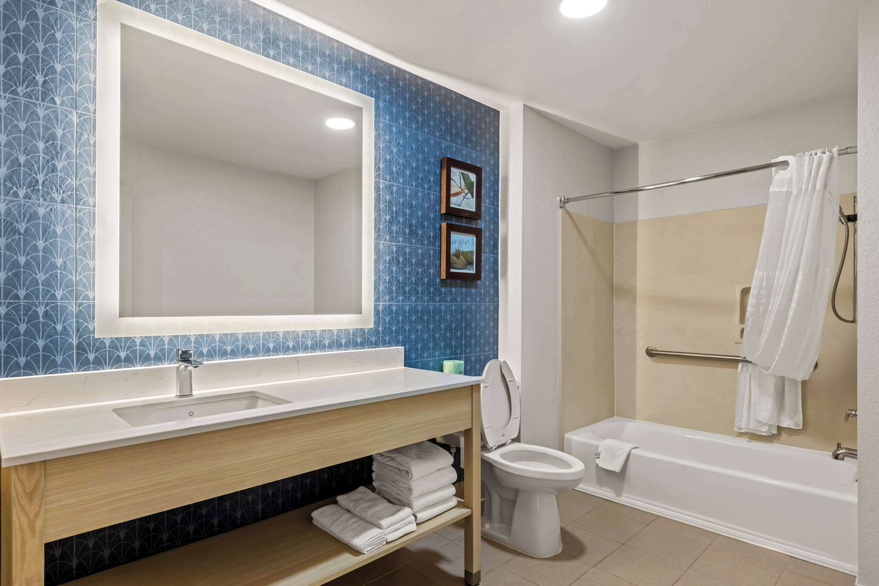 Une salle de bain équipée d’un lavabo, d’un miroir, de toilettes et d’une baignoire.