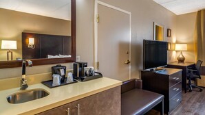 A hotel room with a large mirror, a sink, a coffee maker, a TV, a desk, and a chair. - Comfort Inn & Suites near Six Flags (Lithia Springs)