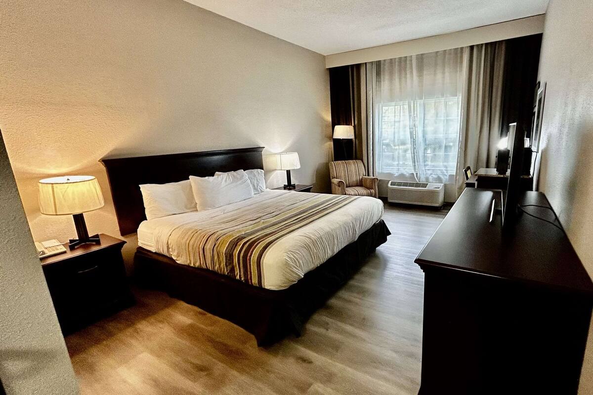 A hotel room with a large bed, a desk, a chair, and a TV.