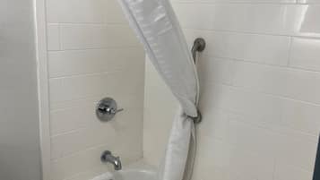A bathroom with a bathtub, a shower curtain, and a toilet.