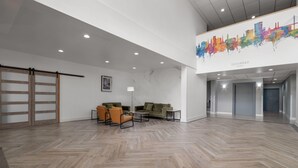 Un hall d’entrée spacieux avec un parquet en point de Hongrie, une porte coulissante et une fresque représentant un paysage urbain sur le mur.
