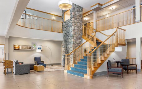 A spacious interior with a stone accent wall, a wooden staircase, and a high ceiling.