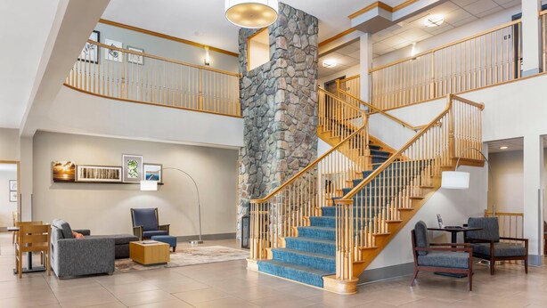 A spacious interior with a stone accent wall, a wooden staircase, and a high ceiling. - Country Inn & Suites by Radisson, Georgetown, KY (Georgetown)