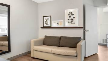 A neutral-toned living room with a beige sofa, a framed abstract artwork, and a framed botanical print on the wall.