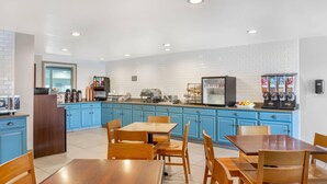 A modern kitchen with blue cabinets, wooden tables, and a coffee station. - Country Inn & Suites by Radisson, Georgetown, KY (Georgetown)