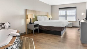 A hotel room with a bed, bedside tables, a desk, a chair, a window, and a bathroom with a bathtub. - Country Inn & Suites by Radisson, Georgetown, KY (Georgetown)