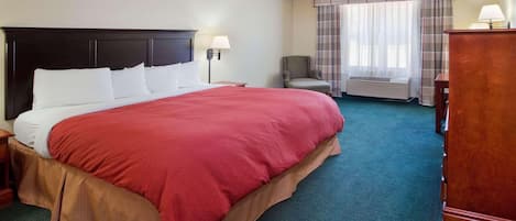 Habitación de hotel con una cama grande, una silla, un escritorio y una ventana con cortinas.