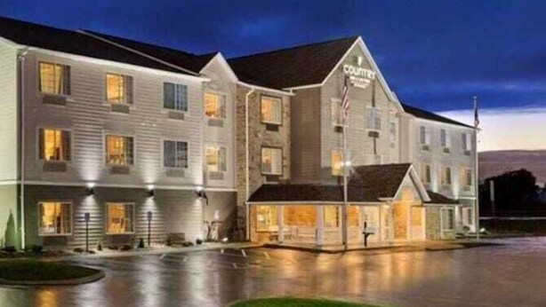 A multi-story hotel with a prominent 'Courtyard' sign, featuring a central entrance with a flag, and a parking lot in front. - Country Inn & Suites by Radisson, Hiram, GA (Hiram)