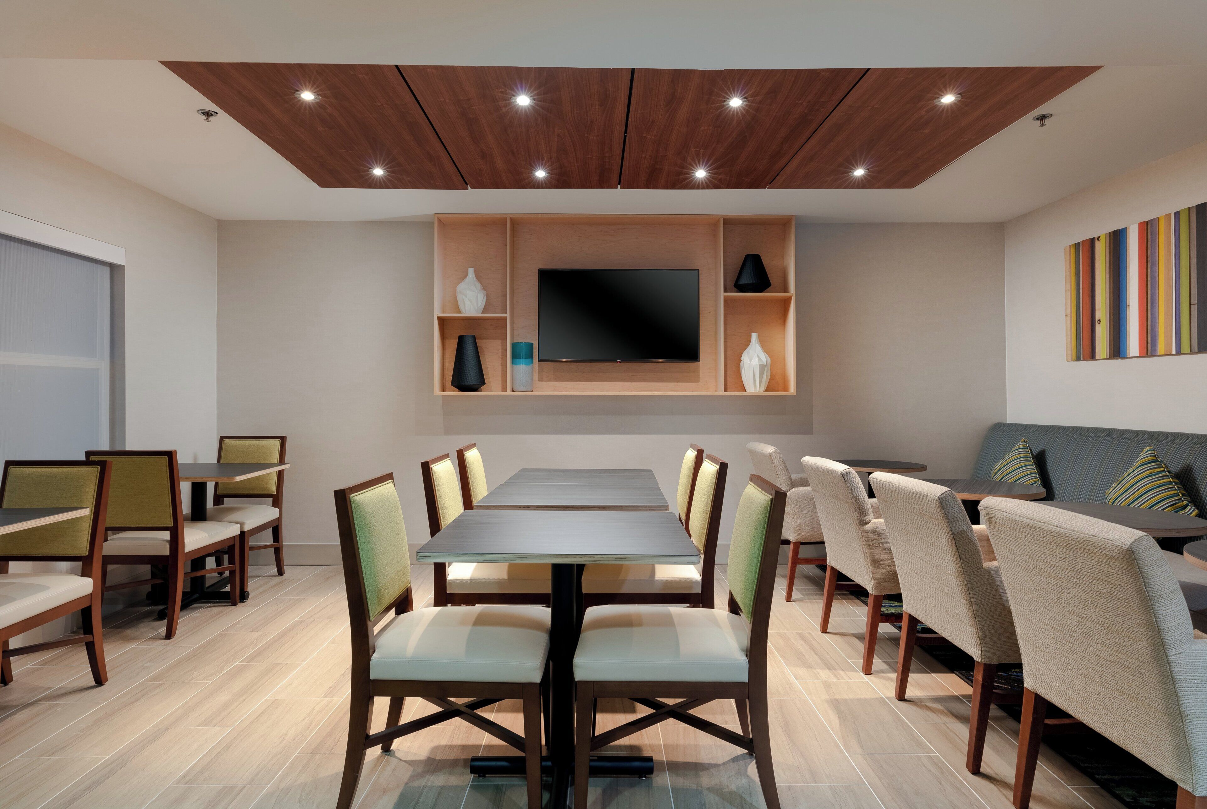 Un espace repas moderne avec une longue table, des chaises, un téléviseur à écran plat et un canapé.