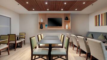 Un espace repas moderne avec une longue table, des chaises, un téléviseur à écran plat et un canapé.