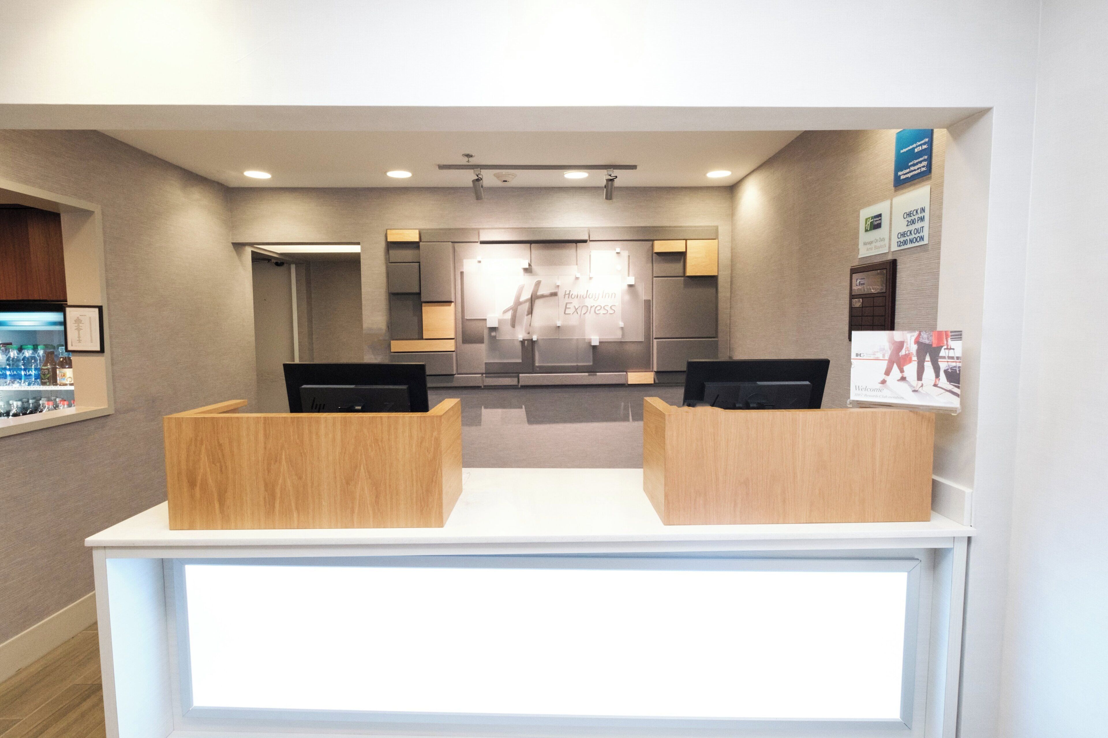 Un espace d’accueil comprenant un comptoir d’enregistrement, un bureau en bois et un panneau fixé au mur.