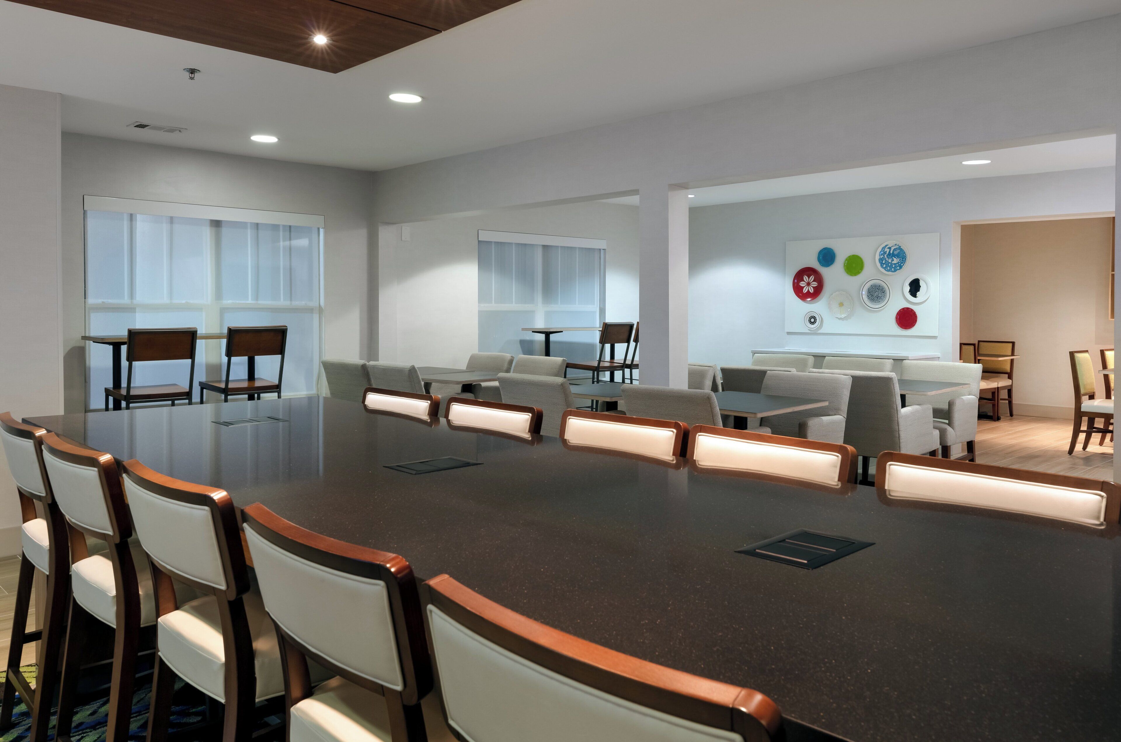 A conference room with a large oval table, multiple chairs, and a wall with decorative plates.