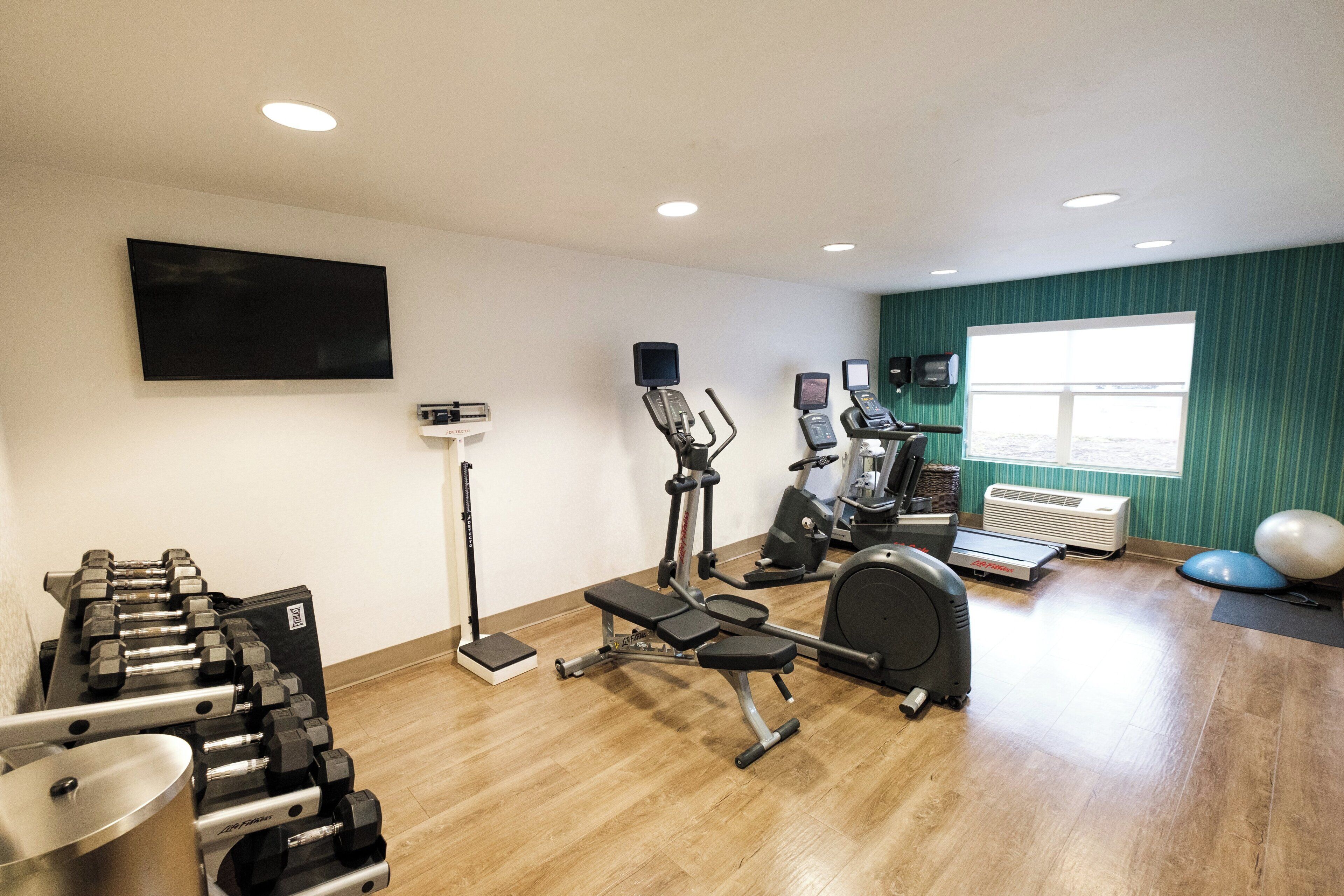 A gym with exercise equipment, a television, and a window with a view.