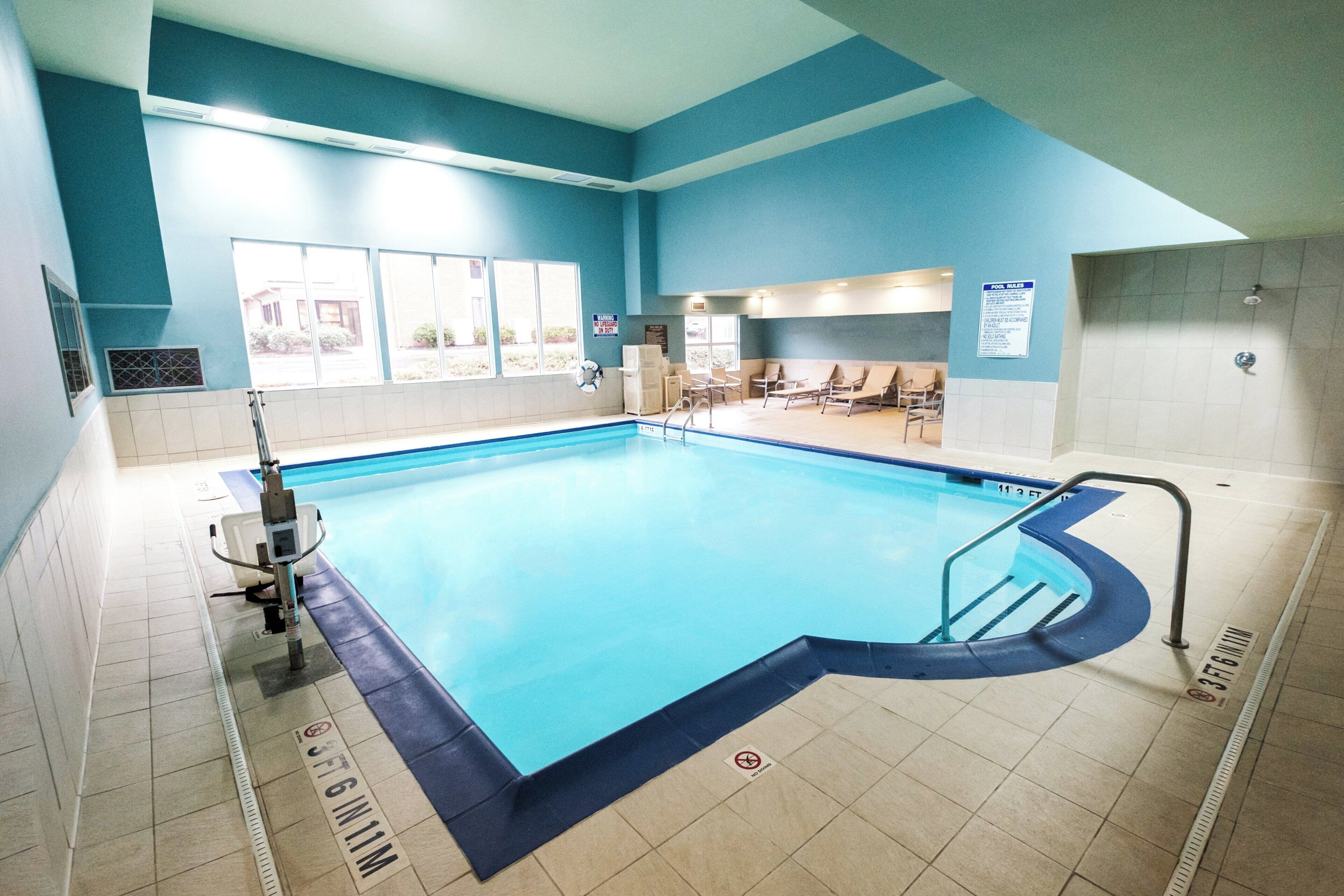 Una piscina con una silla de salvavidas, sillas de descanso y un cartel de piscina.