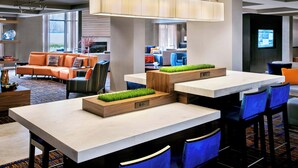 A modern hotel lobby with a bar area, seating, and a television screen. - Courtyard by Marriott Parsippany (Parsippany)