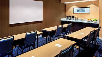 A conference room with a whiteboard, tables, chairs, a coffee station, and a fruit bowl.