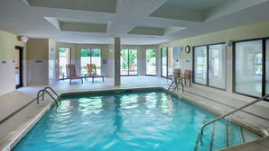 An indoor swimming pool with clear water, surrounded by chairs and a tiled floor. - Courtyard by Marriott Parsippany (Parsippany)
