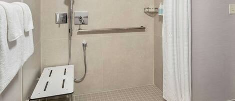 Un espace douche moderne équipé d’un pommeau de douche à main, d’un flexible de douche et d’une barre d’appui.