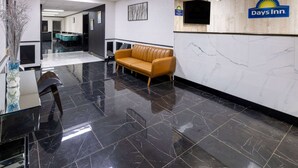 A hotel lobby with a reception desk, a leather sofa, a TV mounted on the wall, and a marble floor. - Days Inn by Wyndham Columbia (Columbia)