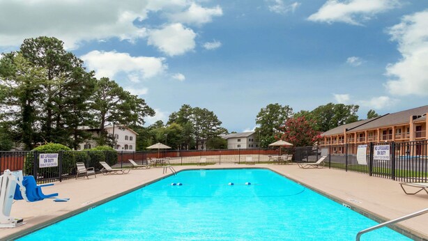 A swimming pool with two lanes, surrounded by lounge chairs and a fence. - Days Inn by Wyndham Columbia (Columbia)