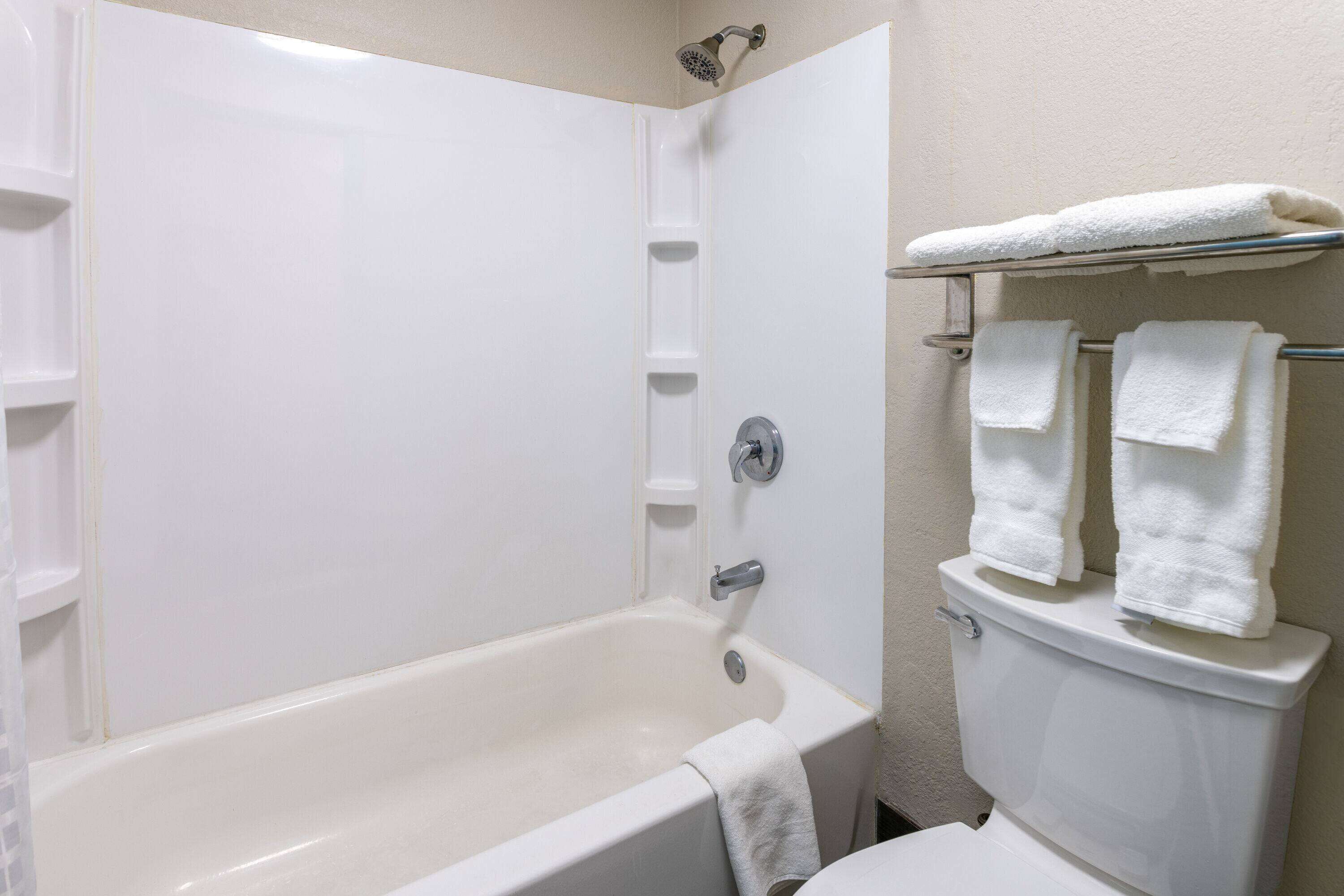 A bathroom with a bathtub, a toilet, and a towel rack with towels.