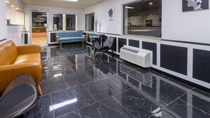A modern lobby with a black marble floor, a blue sofa, a brown leather chair, and a large window with a view of the street. - Days Inn by Wyndham Columbia (Columbia)
