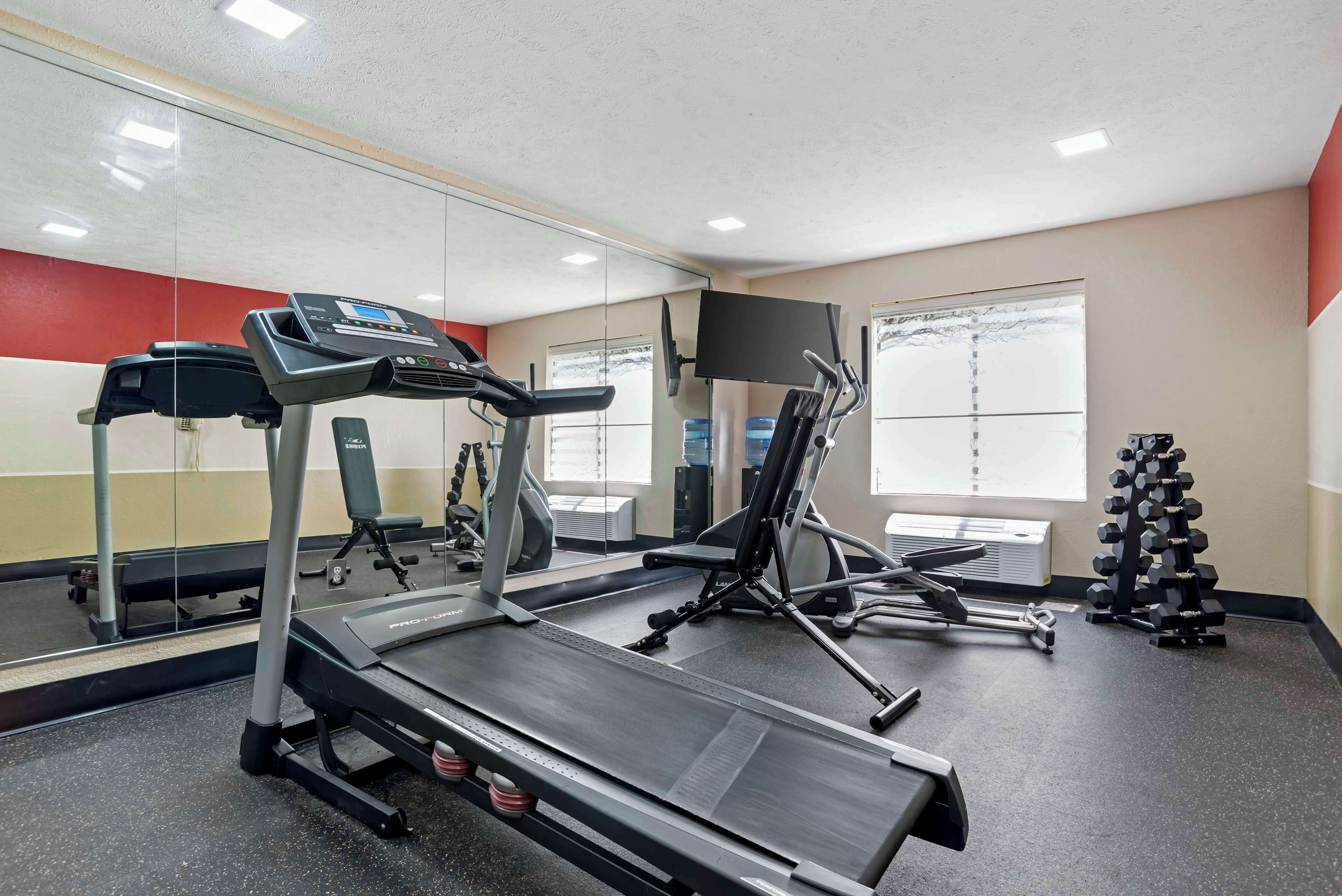 Un gimnasio con cintas de correr, una bicicleta estática y un rack de pesas.