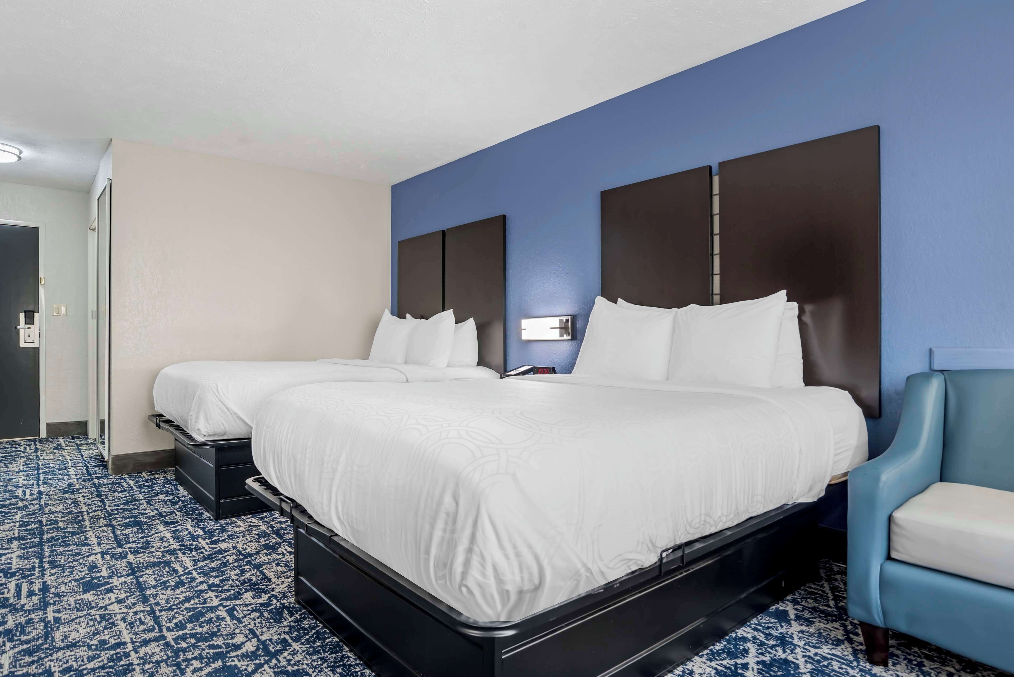 Habitación de hotel con dos camas, una pared azul decorativa y una alfombra estampada.