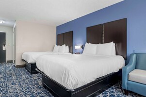 Habitación de hotel con dos camas, una pared azul decorativa y una alfombra estampada.