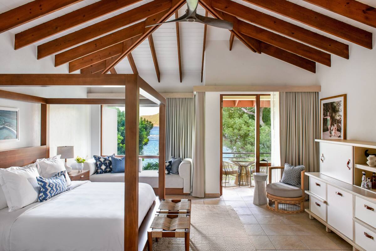 Une chambre avec un grand lit, des tables de chevet, un plafond en bois et une vue sur l’extérieur.