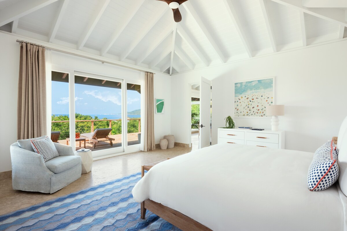 A spacious bedroom with a large bed, a ceiling fan, and a view of the outdoors.
