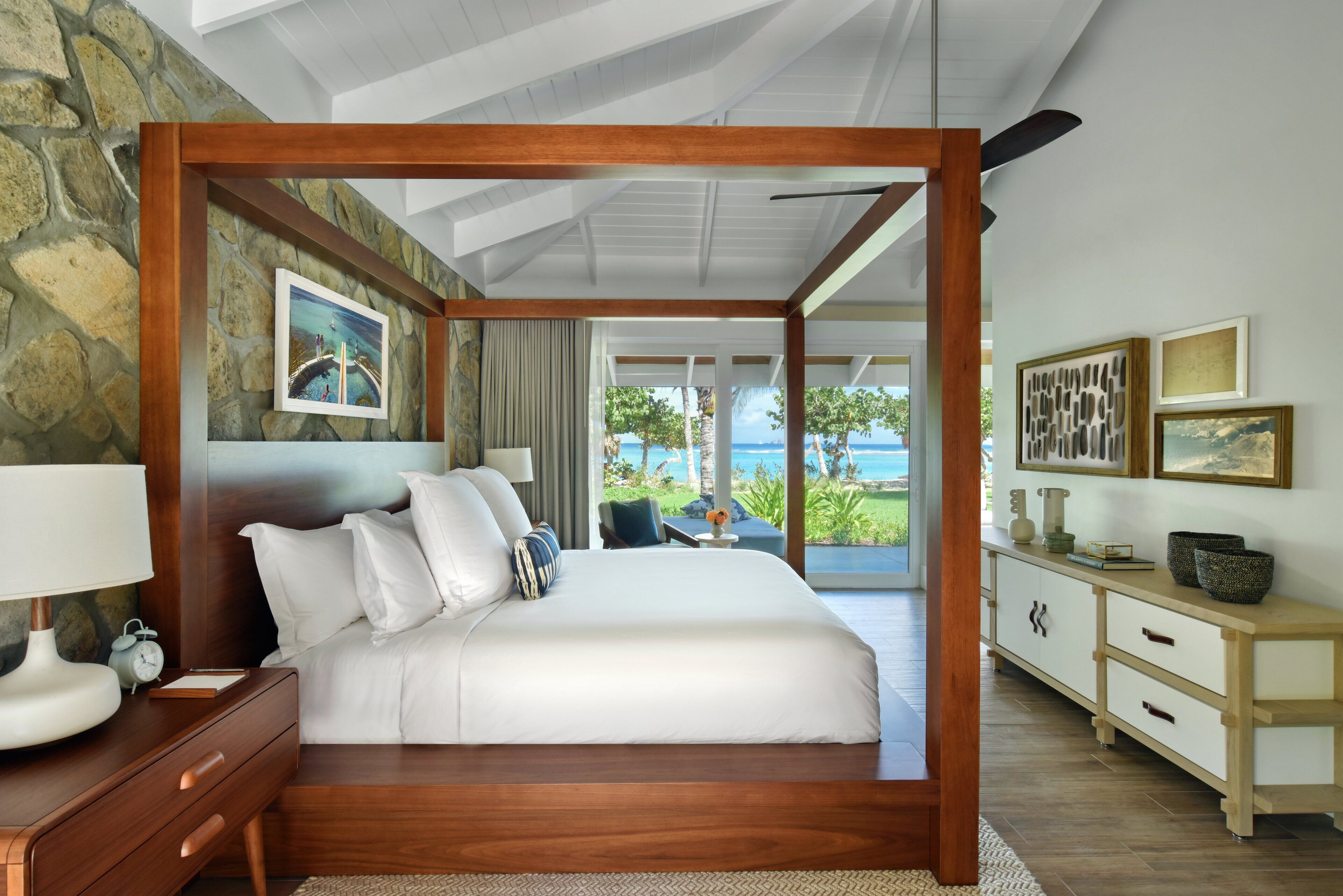 Un dormitorio amplio con una cama grande, cabecera de madera y vista al océano.