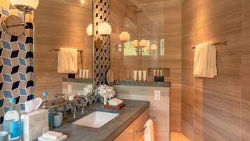 A modern bathroom with a large mirror, two sinks, and a shower area.