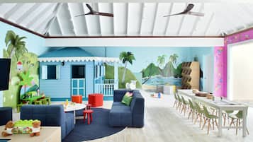 Relax in a vibrant tropical retreat with a stunning mural, blue sofa, and dining table.
