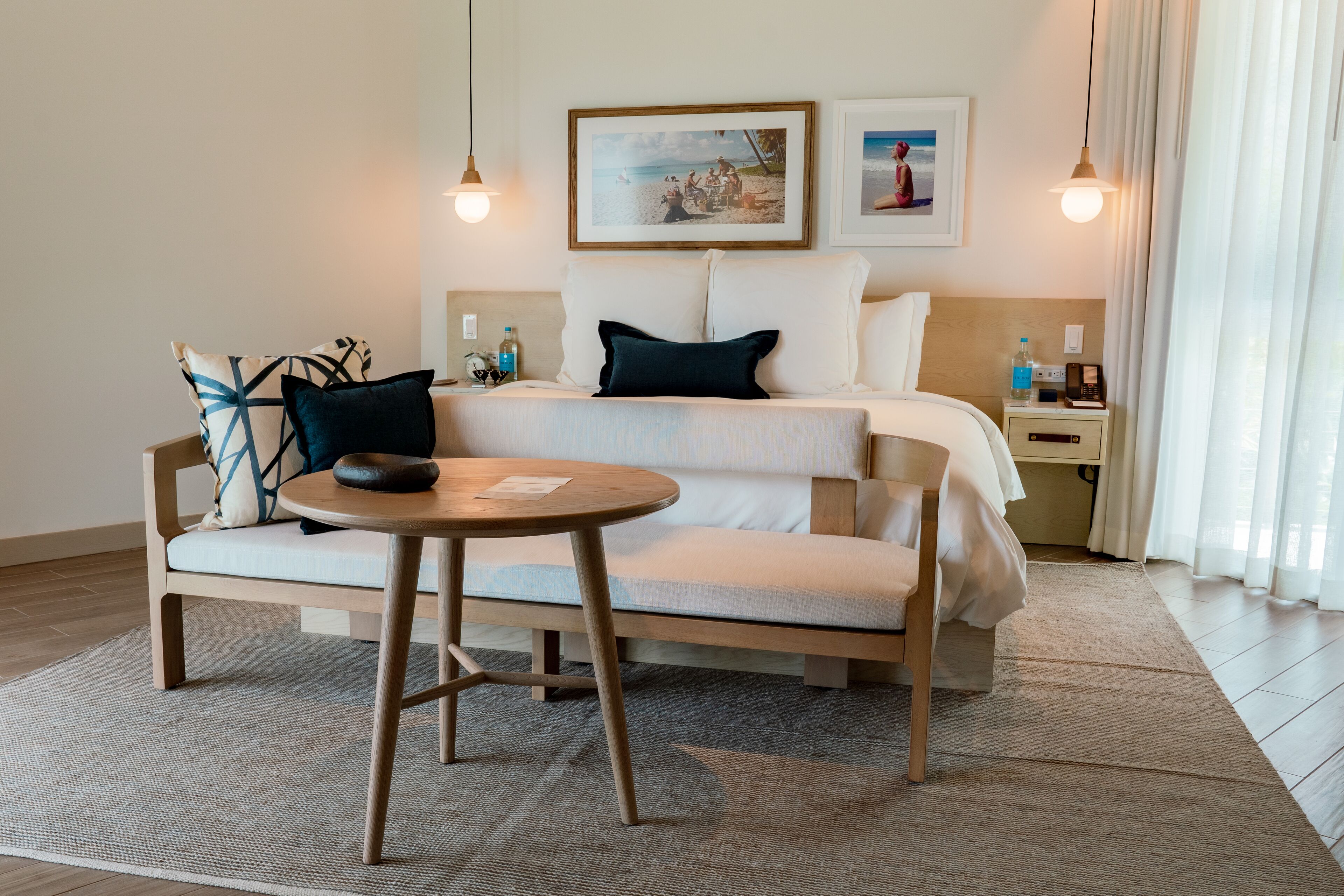 Een hotelkamer met een bed, een bank, een klein rond tafeltje en een nachtkastje met een lamp.