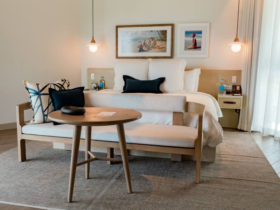 Een hotelkamer met een bed, een bank, een klein rond tafeltje en een nachtkastje met een lamp.